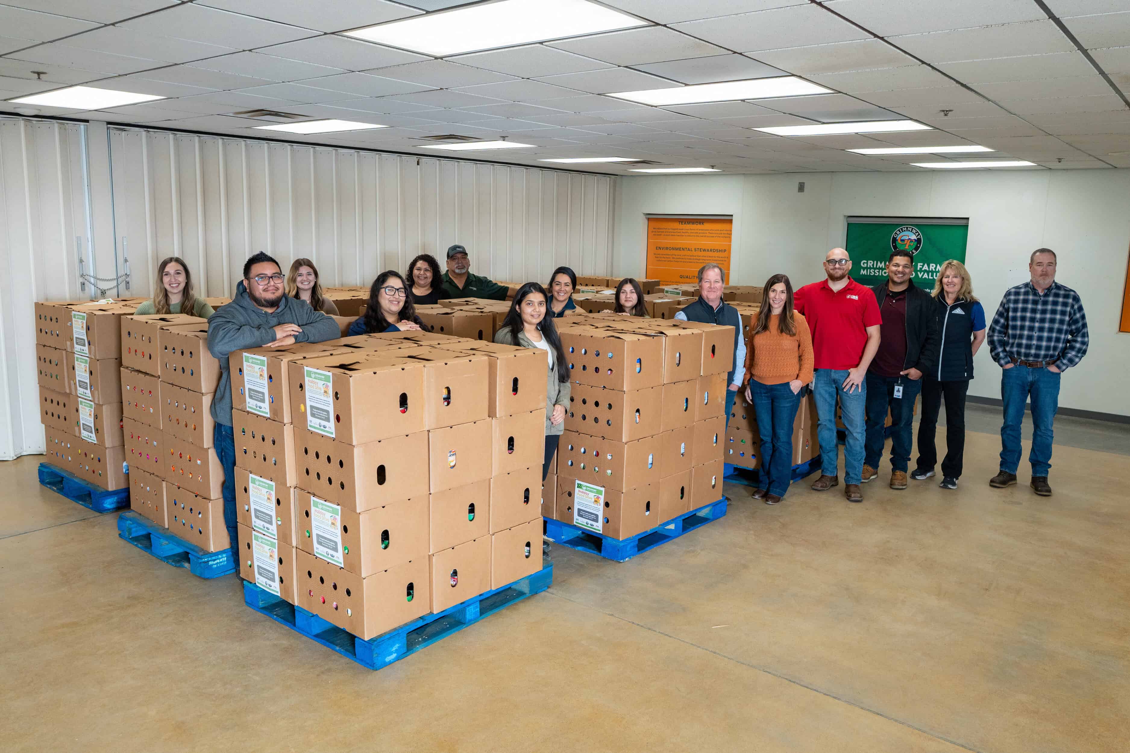 Team standing behind stacked produce boxes indoors