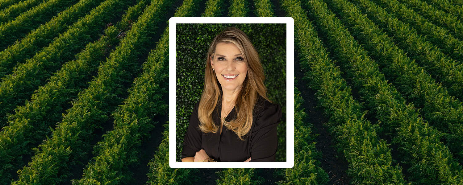 Professional woman smiling against green leafy background