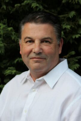 Man in white shirt against green foliage